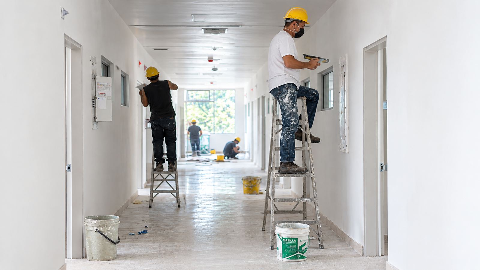 Remodelación de pasillo interior con pintores en andamio